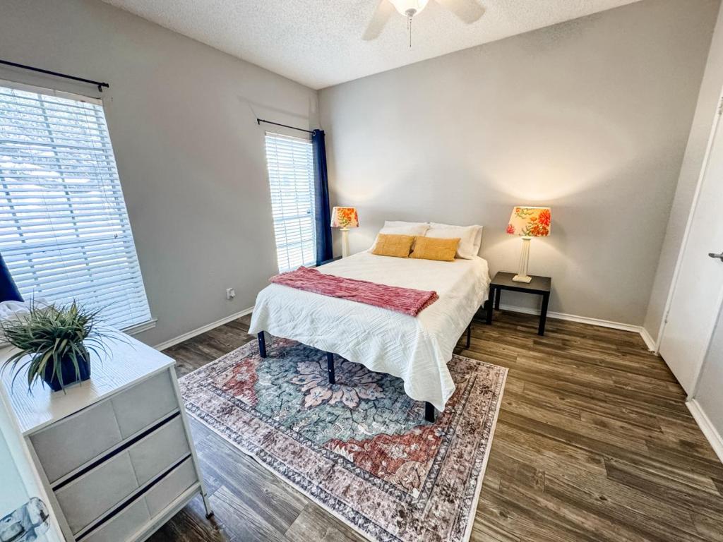 a bedroom with a bed and a dresser and two windows at Spacious Poolside Oasis - Easy Access and Garage in Corpus Christi