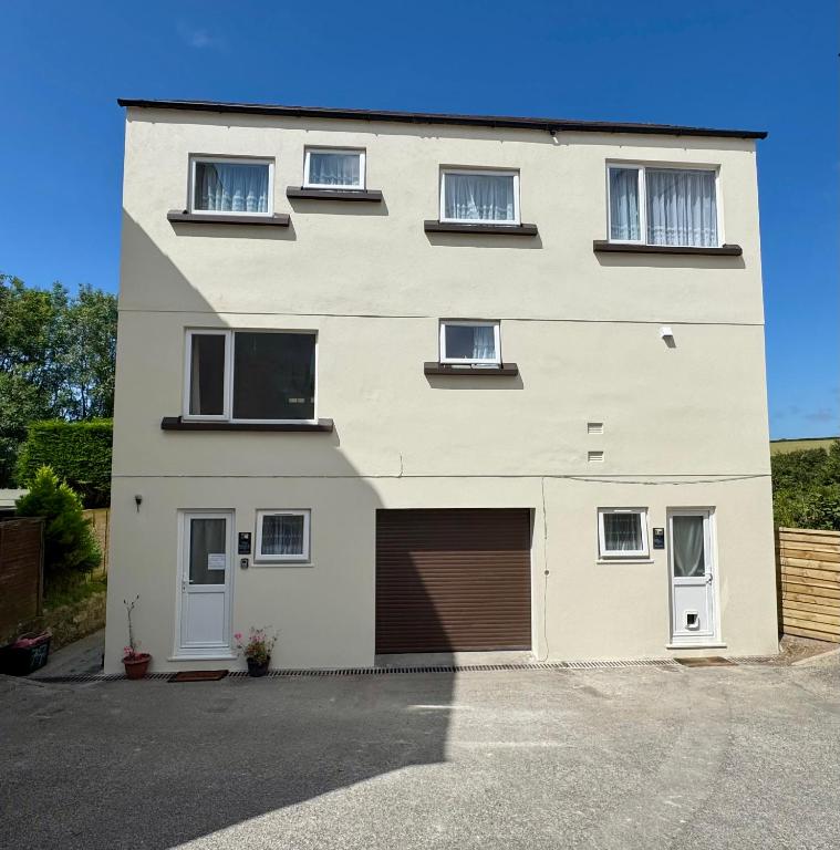 a large white building with a garage at The Shack 1 bedroom apartment in Newquay