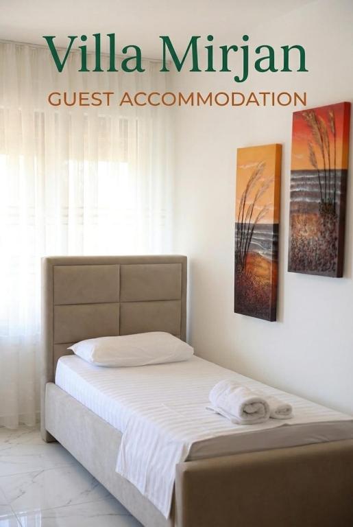 a bed in a room with a sign that reads villa miron guest association at Villa Mirjan in Sarandë