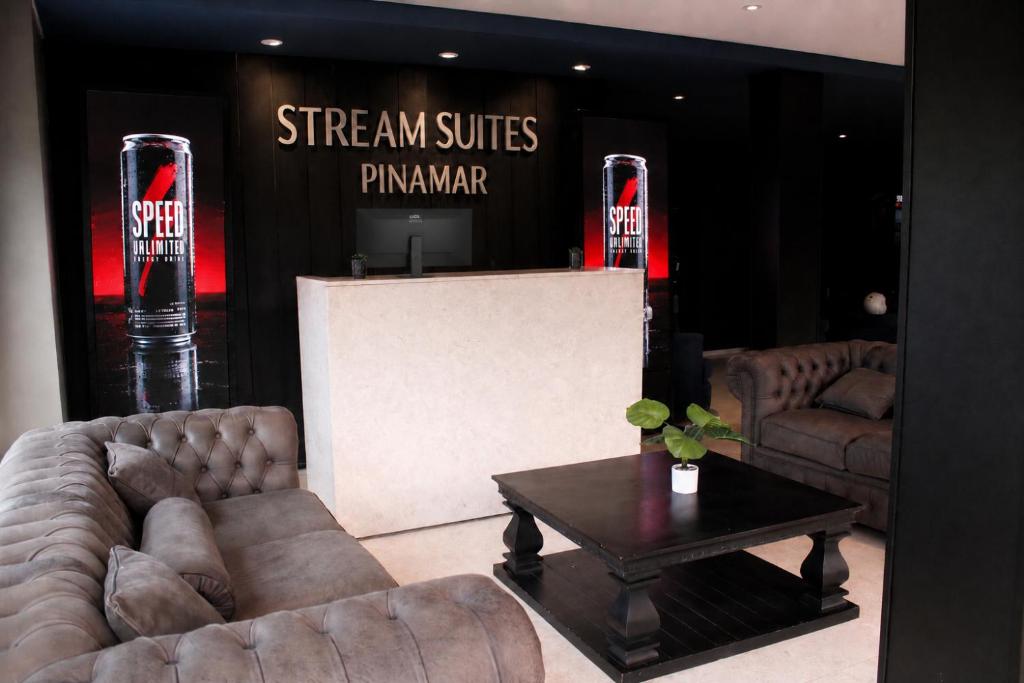 a living room with couches and a table and a sign at Stream Suites Pinamar in Ostende