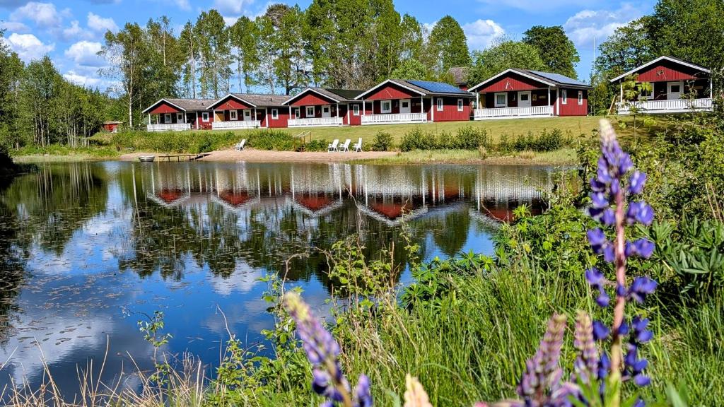 a row of red and white buildings next to a lake at Stor älg in Dalskog