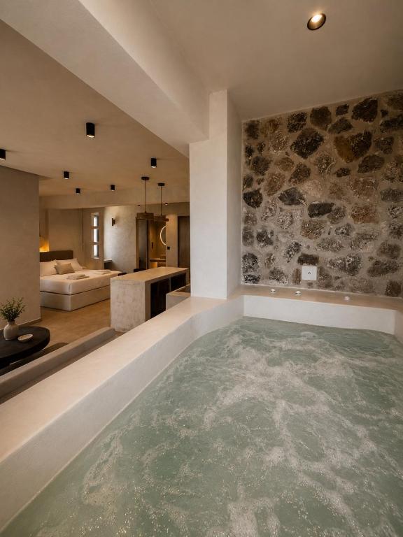 a large swimming pool in a room with a stone wall at Ethos Suites in Agios Prokopios