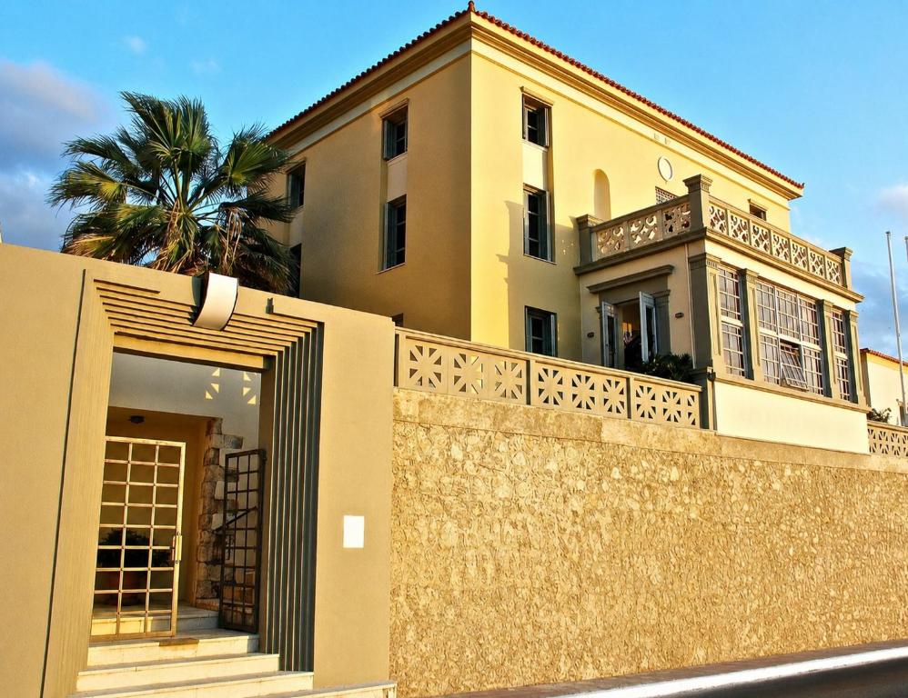 a yellow house with a fence and a palm tree at Villa Andromeda in Chania