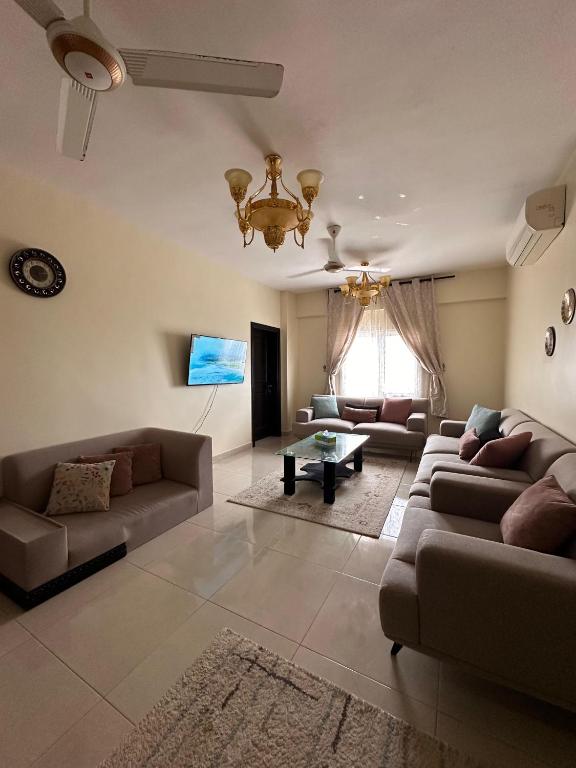 a living room with two couches and a chandelier at شقة كبيرة مؤثثة بالكامل in Salalah