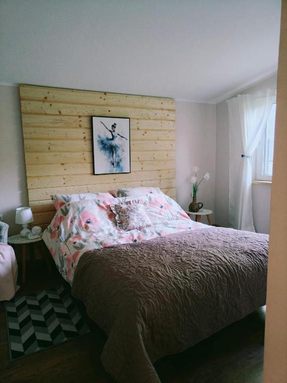 a bed with a wooden headboard in a bedroom at Apartamenty nad Brdą in Zapędowo