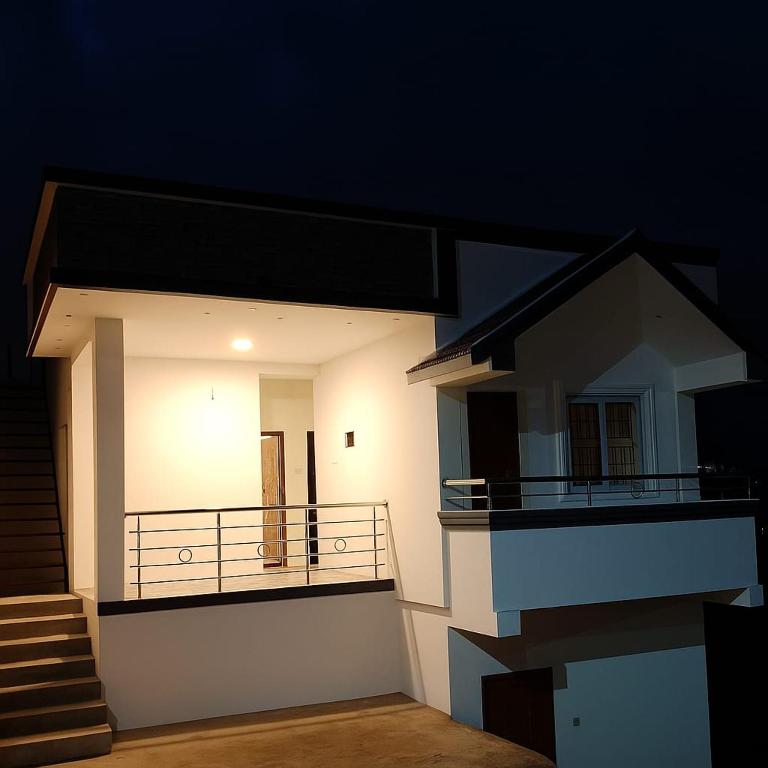 a small white house with a balcony at night at Mithra Cottages individual Villa in Ooty