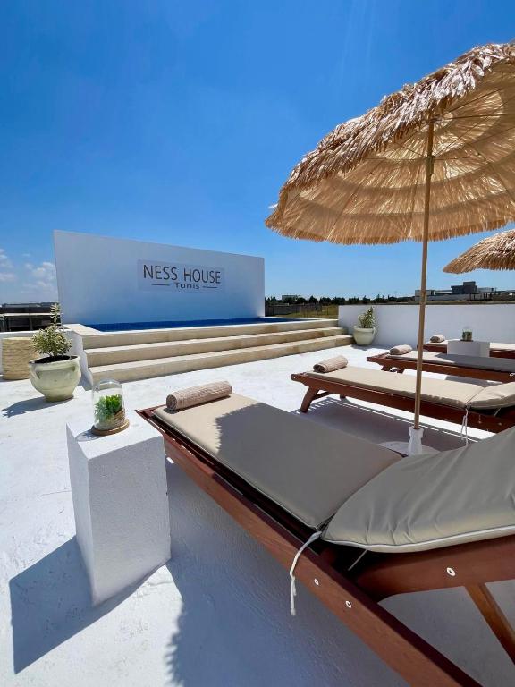 a resort with two beds and an umbrella at Pool House et Rooftop Hammamet in Dar Hamad Jedidi