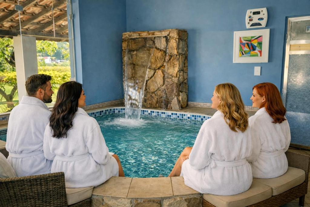 a group of people sitting around a pool with a waterfall at Hotel - Pousada 3 Marias in São Pedro