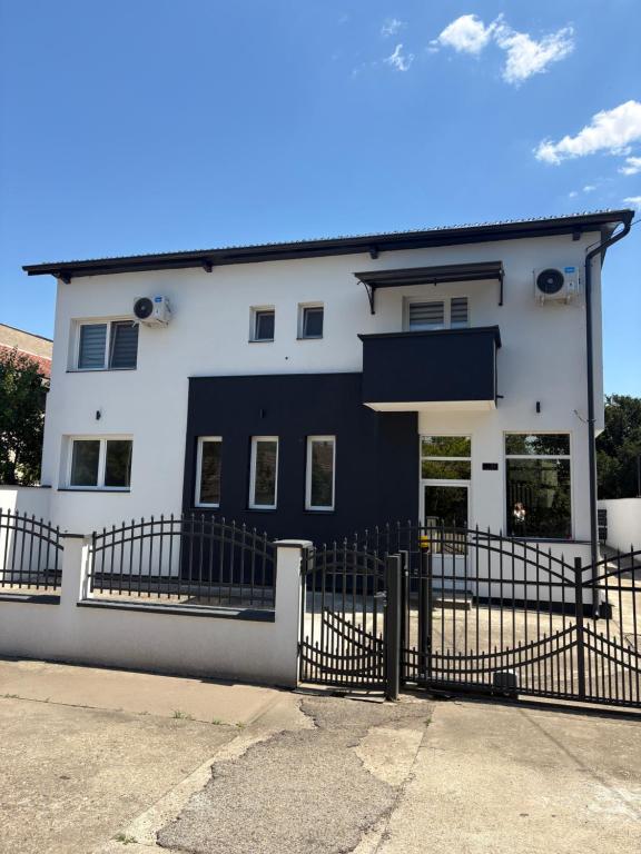 a white building with a fence in front of it at Apartmani Harmonija in Vrbas