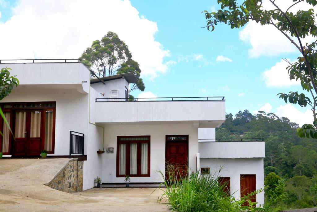 a white house with red doors and trees at Lush Home in Bandarawela