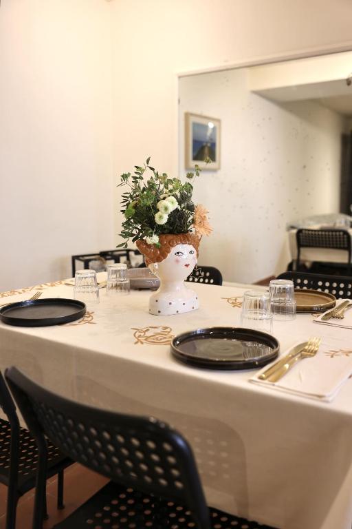 a table with a white vase with flowers in it at B&B Camilla in Rimini