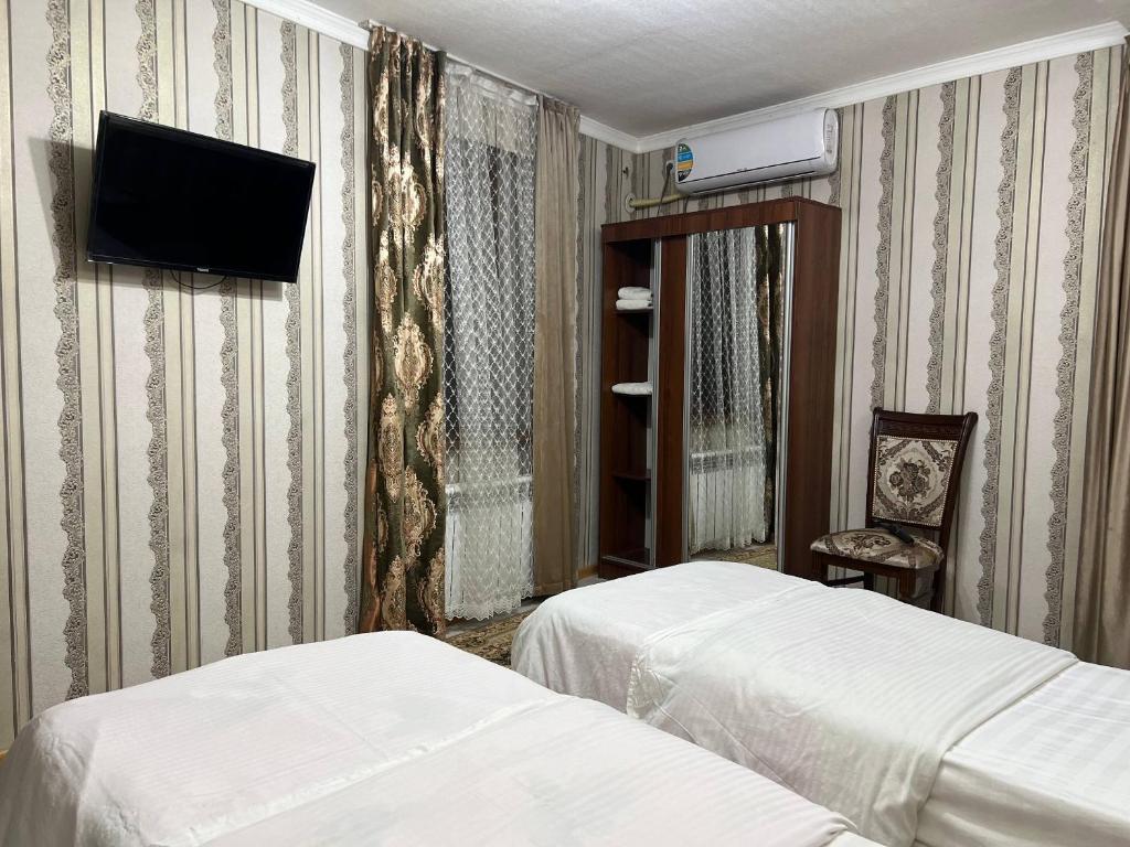 a hotel room with two beds and a tv on the wall at El Emir in Samarkand