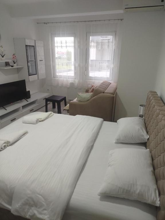 a bedroom with a large white bed and a couch at Vea in Banja Koviljača