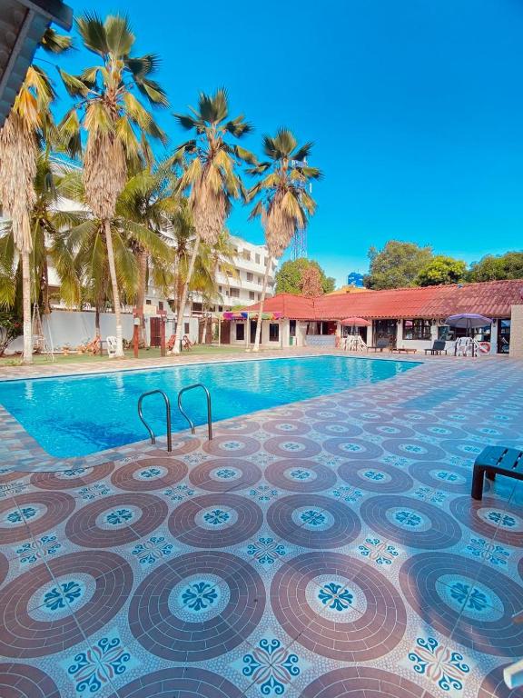 a swimming pool with palm trees in the background at Hotel PalmaSol in Ricaurte
