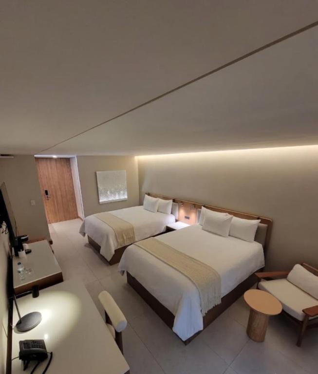 a hotel room with two beds and a desk at Hotel Alameda in Tegucigalpa