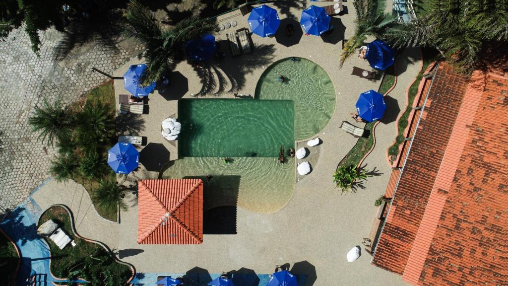 an overhead view of a swimming pool with blue umbrellas at Hotel Rural Vale das Nascentes in Salesópolis