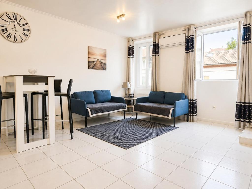 a living room with chairs and a clock on the wall at sejour climatisé avec chambres avec ventilateurs in Bourgoin