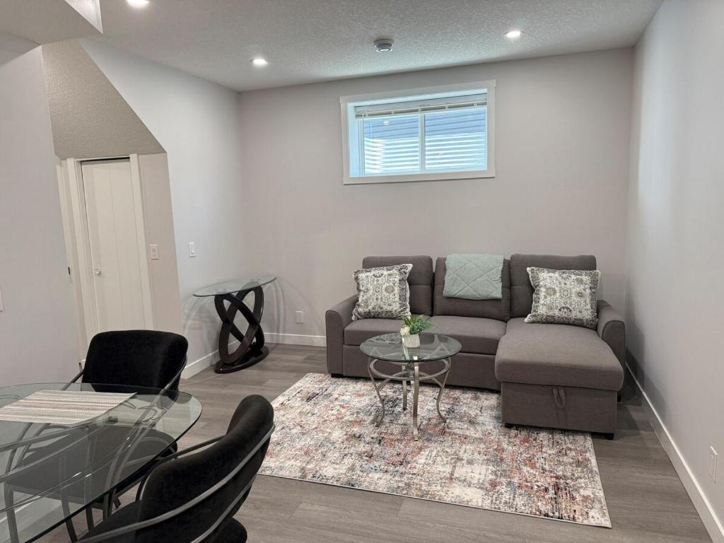 a living room with a couch and a glass table at Cozy Suite Near Airport in YYC