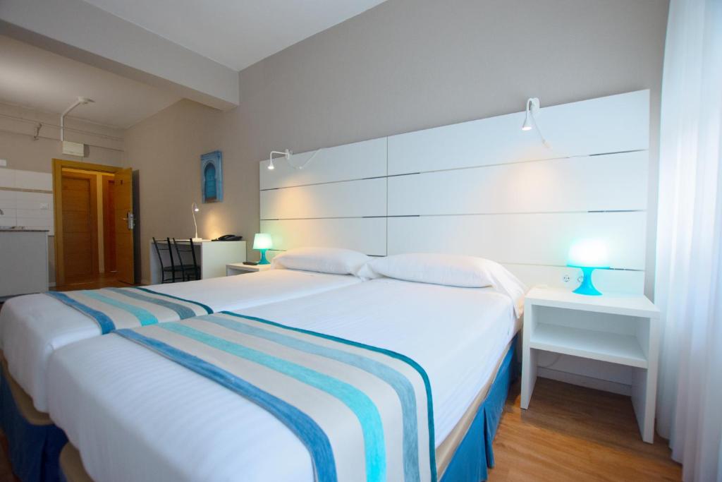 a bedroom with a large white bed and a desk at Estudios Aránzazu in Santander
