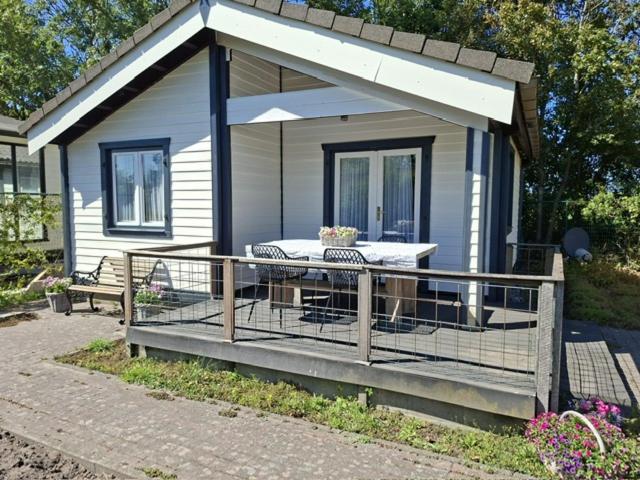 a small house with a deck with a table at Oase van rust in Poortvliet