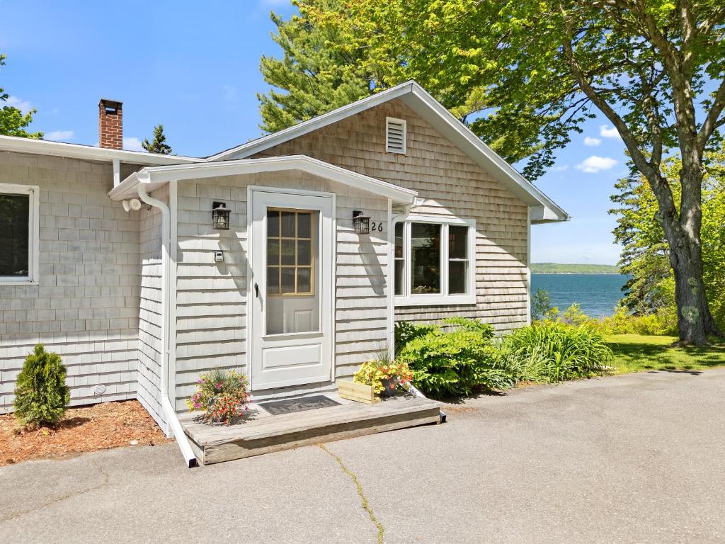 a white house with a porch and a door at Charming home with stunning bay views, sunroom, gazebo, deck, & grill in Trenton