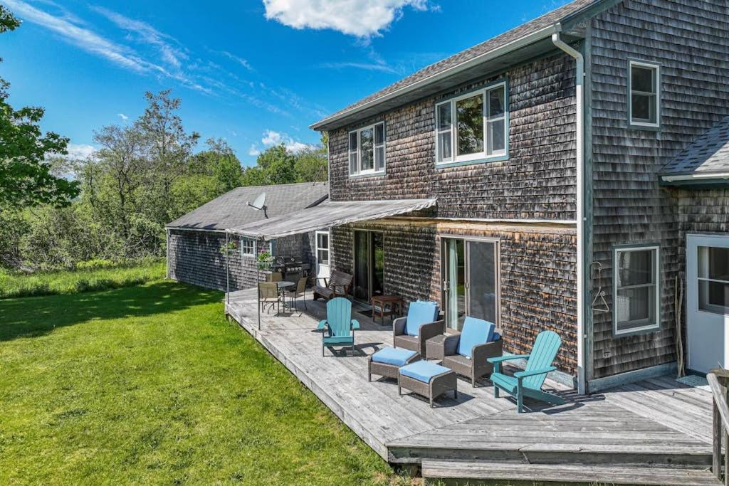 a brick house with a deck with blue chairs at Waterfront stay with scenic deck, grill, smart TVs, shore access - dog-friendly in Penobscot