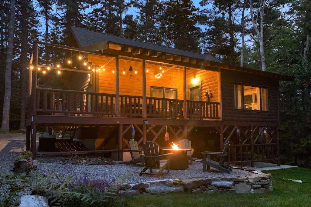 a log cabin with a deck and lights on it at Amazing All-Season Sprucewold Cabin w/ Private Beach Club Access Dog-friendly in Boothbay Harbor