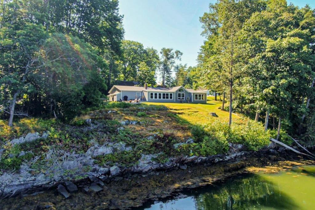 a house on a hill next to a river at Gorgeous Waterfront Home on Westport Island with 2 Sunrooms in Montsweag