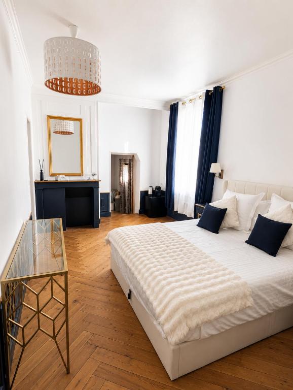 a bedroom with a large white bed and a table at Chambre Oolong Familiale in Cormeilles