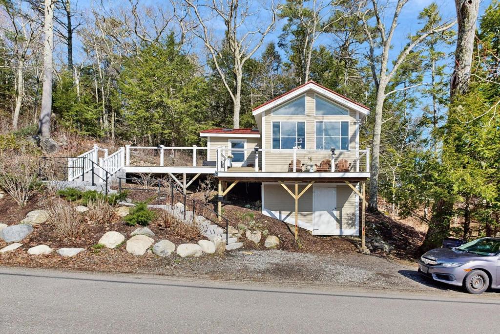 a house on a hill with a car parked in front at Charming cottage with a spacious deck overlooking the Megunticook River in Camden