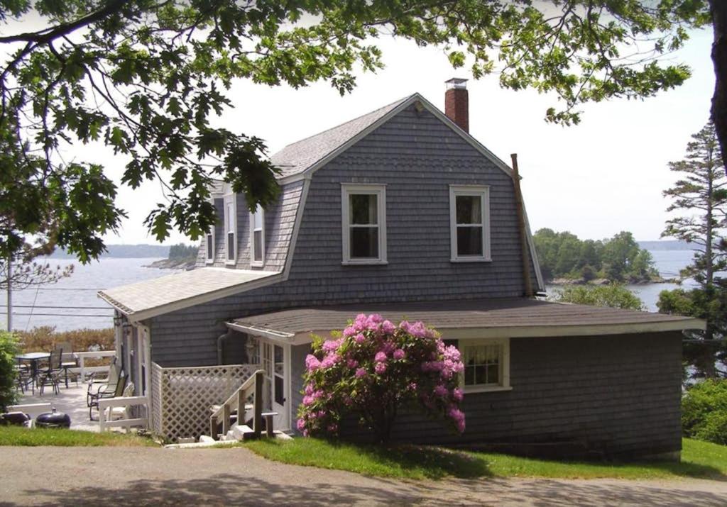 a black house with pink flowers in front of it at Dog-friendly, bayfront home - gorgeous ocean views, private balcony & fireplace in East Boothbay