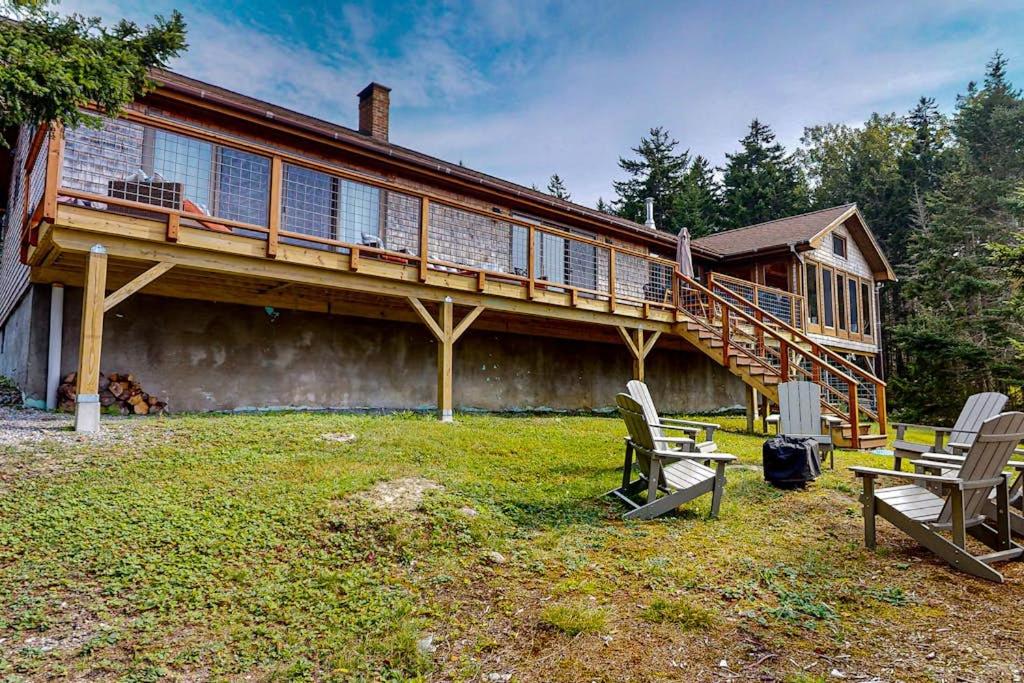 a house with a deck and chairs in the yard at Renovated oceanfront home with stunning view & pebbly beach - snowbird-friendly in Saint George