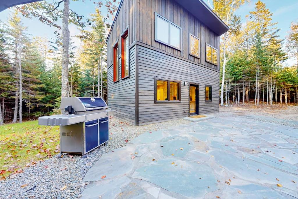 a house with a grill in front of it at Contemporary home with woodstove, firepit, 2 kitchens & fast WiFi- walk to beach in Marlboro