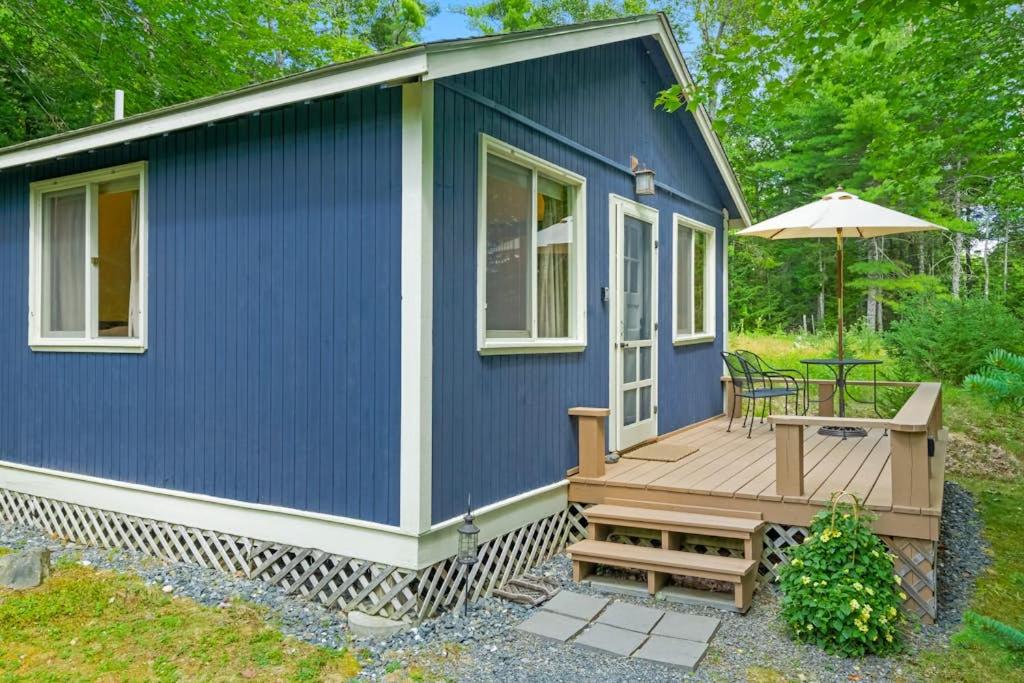 a blue tiny house with a deck and an umbrella at Woodland Home near Long Pond w/ Spacious Living Area, Full Kitchen & Deck in Somesville