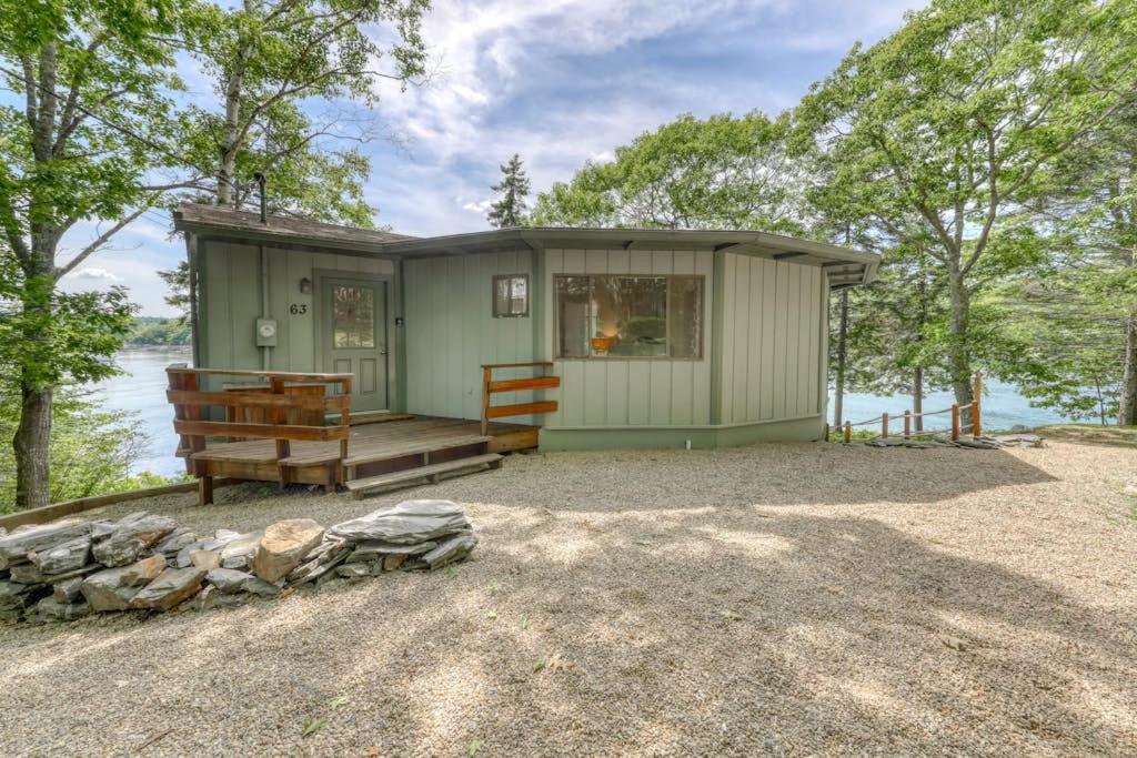 a green tiny house on the shore of a lake at Unique oceanfront home with a deck, tons of natural light, & amazing views in Wiscasset
