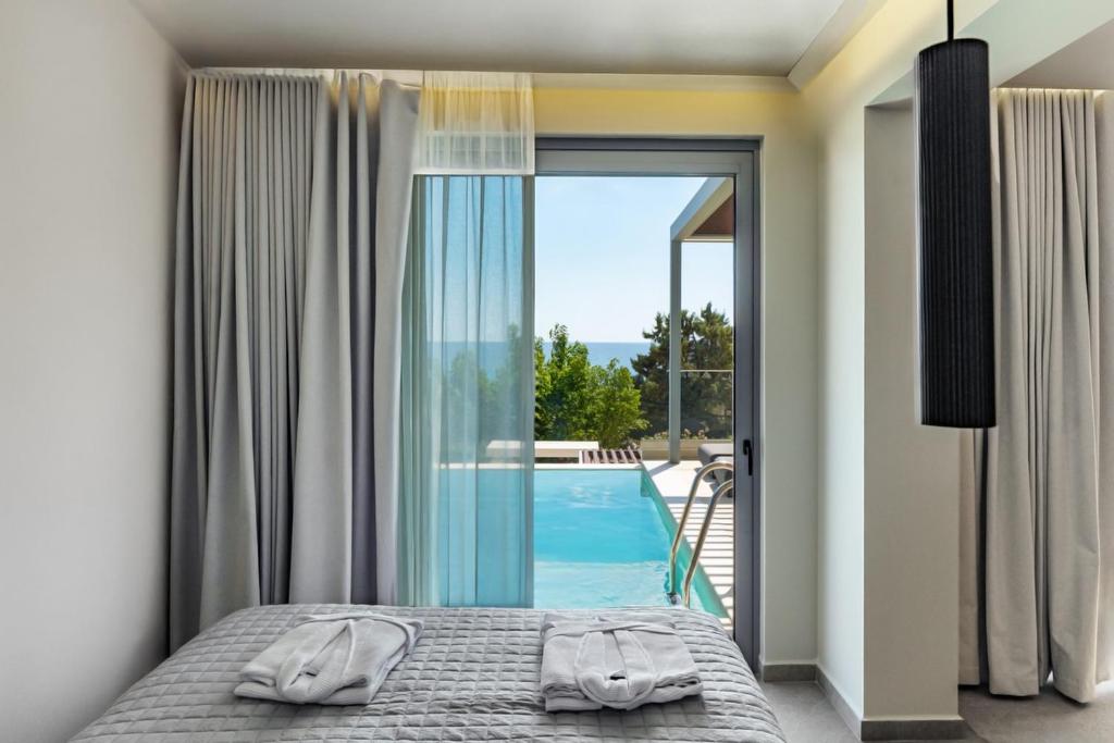 a bedroom with a bed and a view of a swimming pool at Merivian Seaside Suites in Kanali