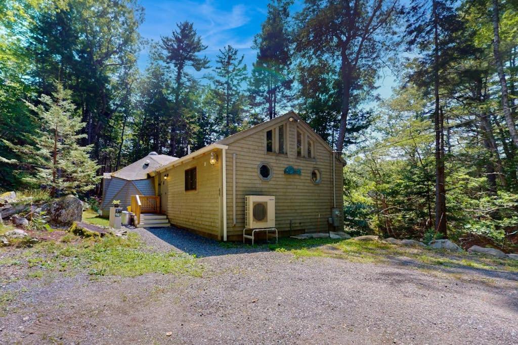 a small yellow house in the middle of a forest at Geodesic Dome w/ Riverfront Deck, Lovely Views, & High-Speed WiFi - Dogs Welcome in Boothbay