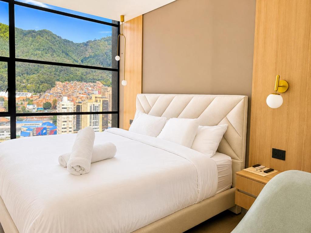 a bedroom with a white bed with a large window at Apartaestudio Centro Internacional UTEK in Bogotá