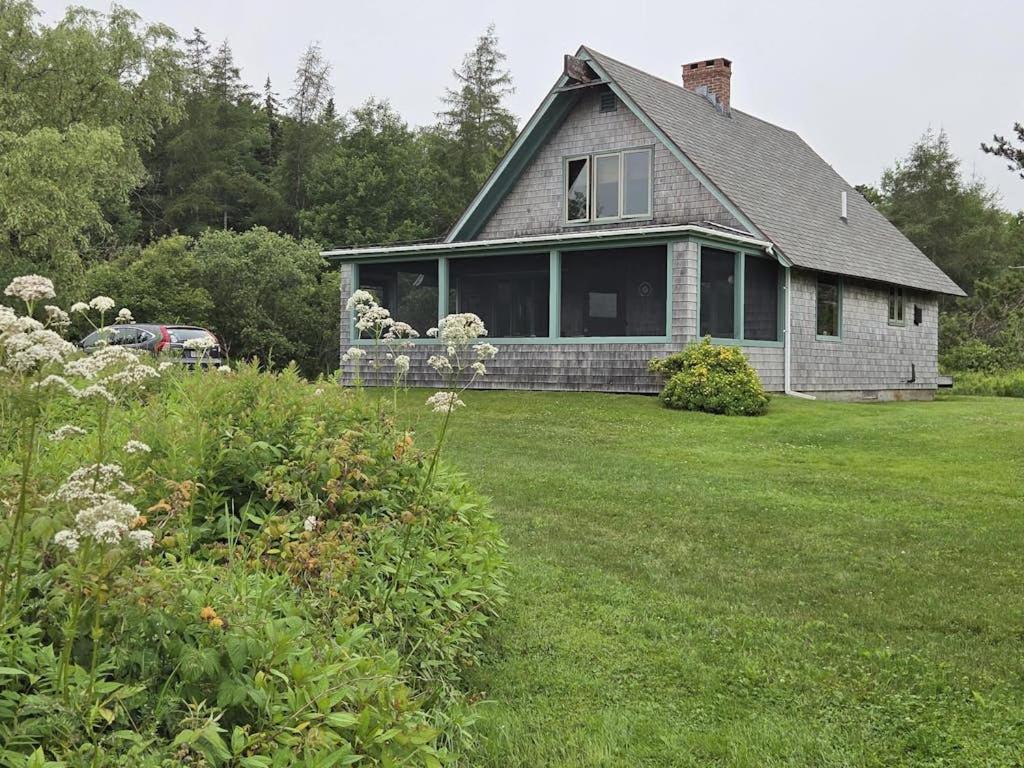 a house with a yard with a grass field at Peaceful coastal cabin with screened porch, water view of the cove, dog-friendly in Owls Head