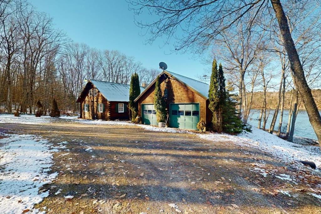 a log cabin in the snow next to a road at Riverfront retreat with a furnished deck, washer/dryer & fast WiFi in Boothbay