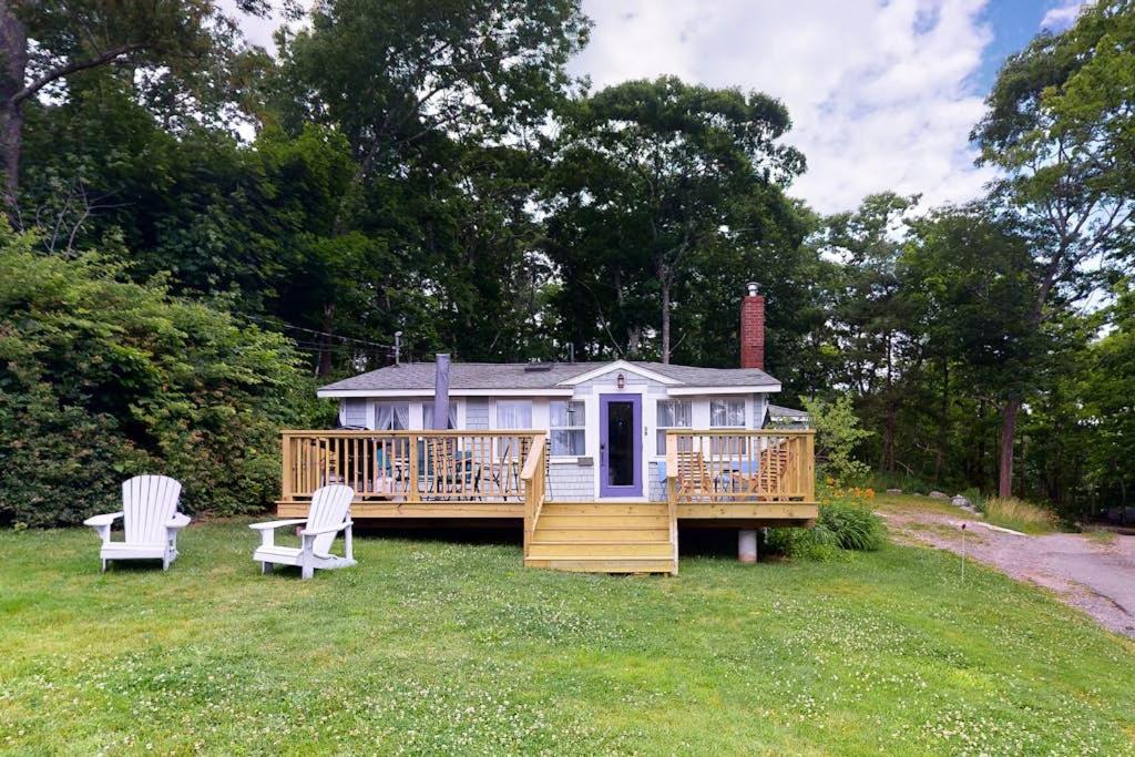a large house with a deck and two chairs at Dog-friendly Fisher Hill home with patio and wood stove - walk to the harbor in Boothbay Harbor
