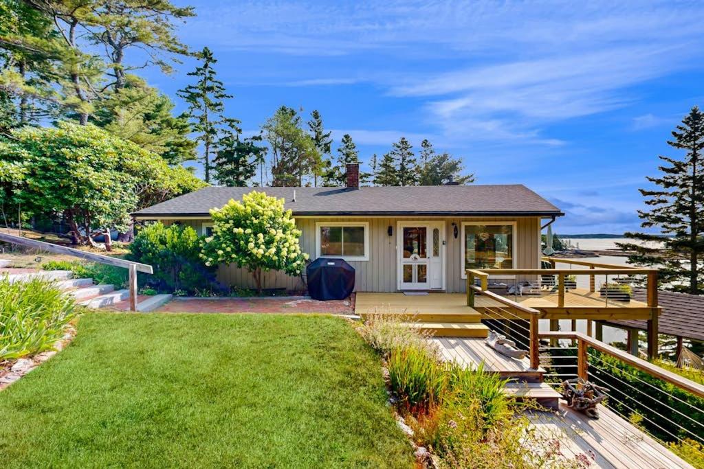 a small house with a deck and a yard at Stunning artist's retreat with ocean view & amazing deck, near Reid State Park in Georgetown