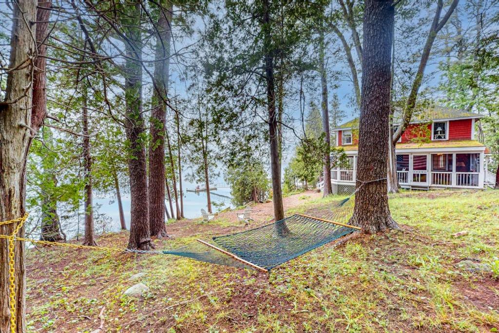 a house in the woods with a net at Cozy, Waterfront Cabin-Style Gem with Private Dock and Lovely Views in East Harpswell