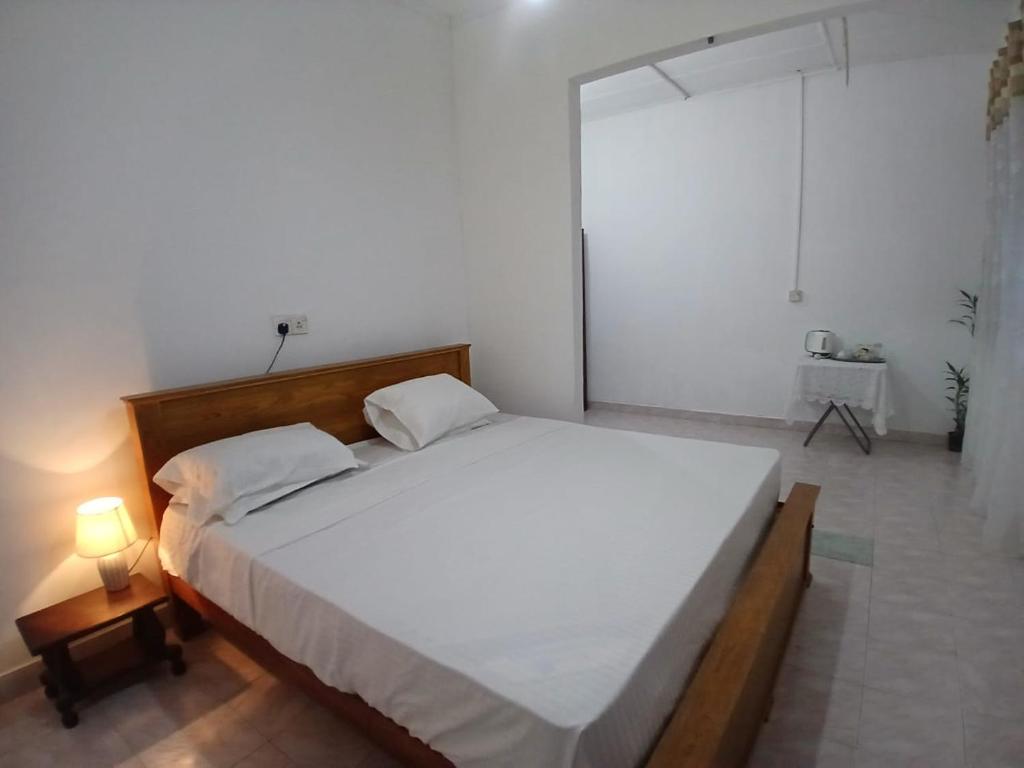 a large white bed in a bedroom with a lamp at The Emerald Ceylon - Colombo in Pannipitiya