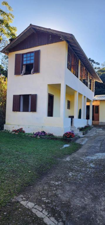 a large white house with windows and a yard at Aconchego Mineiro in Visconde De Maua
