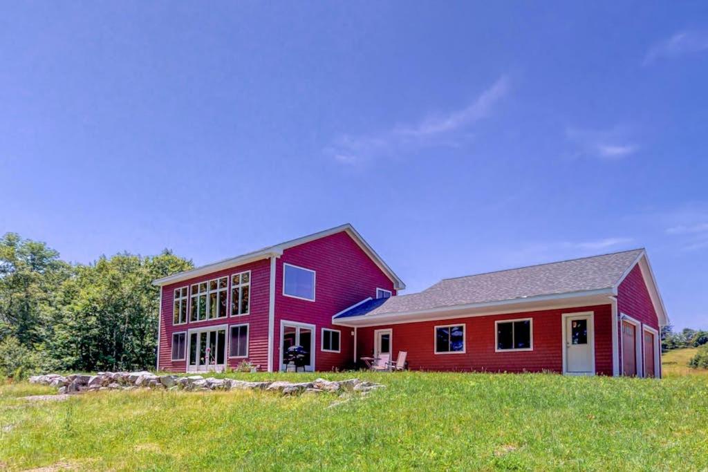 ein rotes Haus auf einem grünen Feld in der Unterkunft Bayfront home with gorgeous water views, dock, outdoor patio, fireplace in Bowdoinham