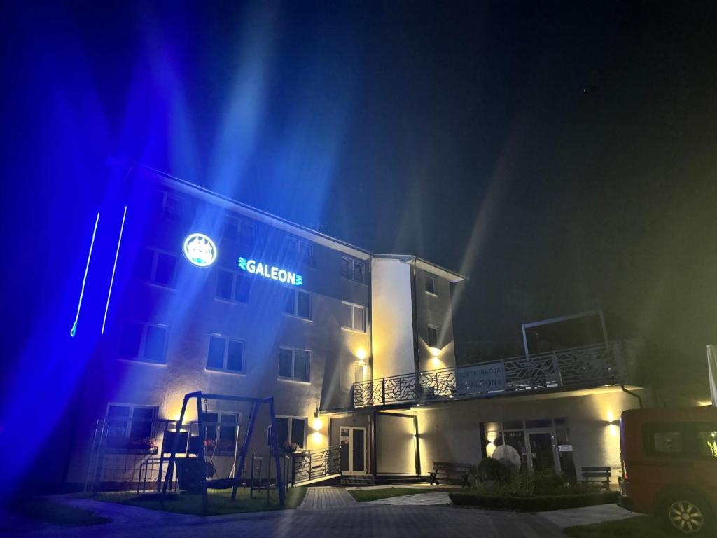 a building with a sign on it at night at Willa Galeon in Sarbinowo