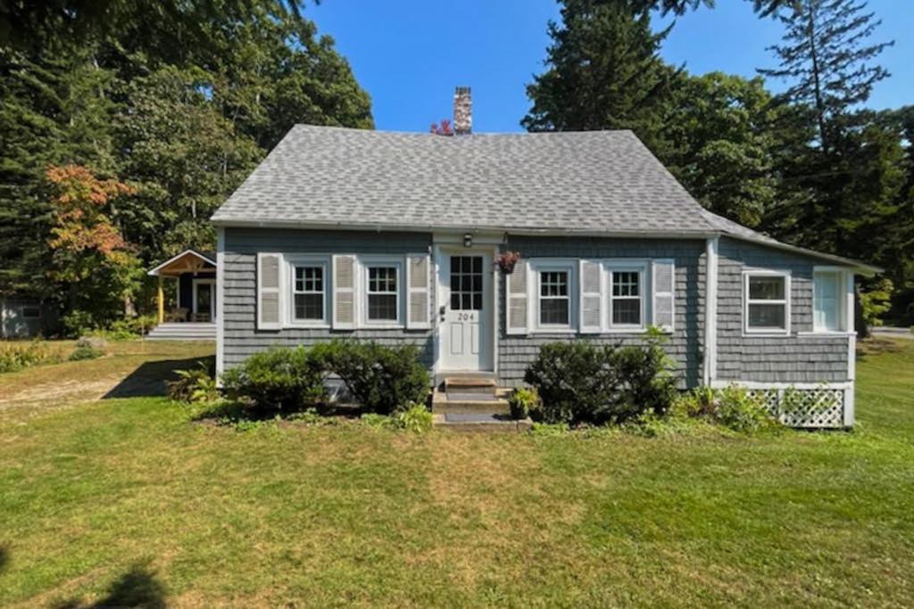 a small house on a field with a yard at Charming Boothbay Harbor cottage with partial AC, full kitchen, and sun room in Boothbay Harbor