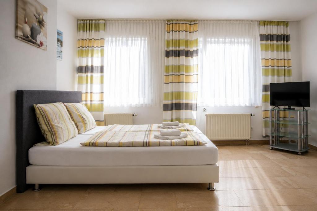 a bedroom with a bed and a tv and windows at Hotel Restaurant Neffelthal in Kerpen