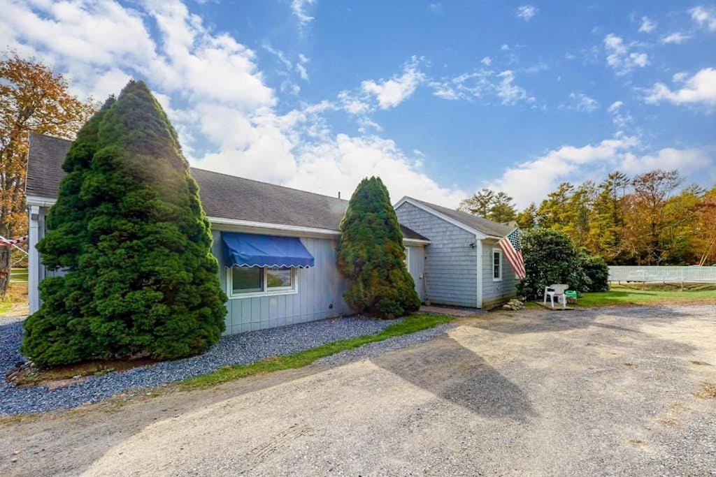 a house with two large trees in front of it at Colorful duplex home with a large yard, deck, WiFi, & ideal Midcoast location in Boothbay